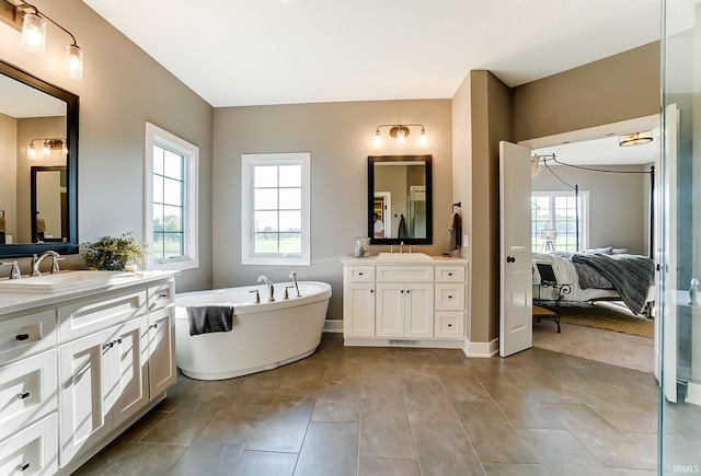 ensuite bathroom featuring a soaking tub, a wealth of natural light, ensuite bathroom, and a sink