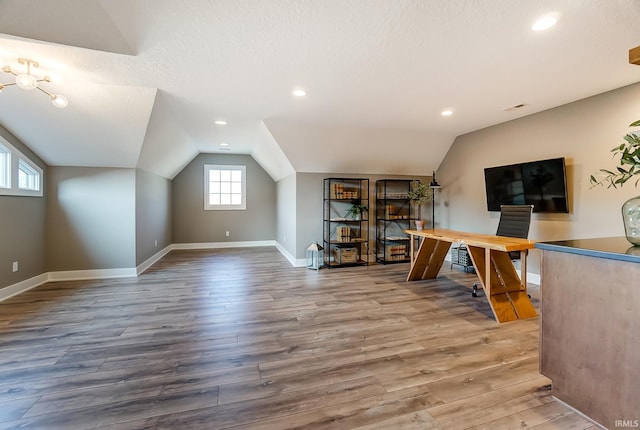 interior space with wood finished floors, baseboards, visible vents, lofted ceiling, and a textured ceiling