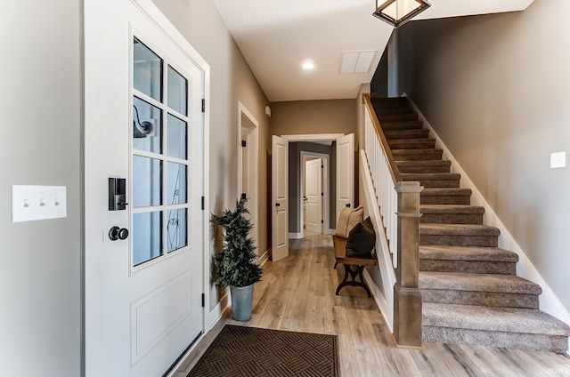 entryway featuring light wood finished floors, stairway, and baseboards