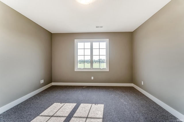 unfurnished room with visible vents, baseboards, and dark colored carpet