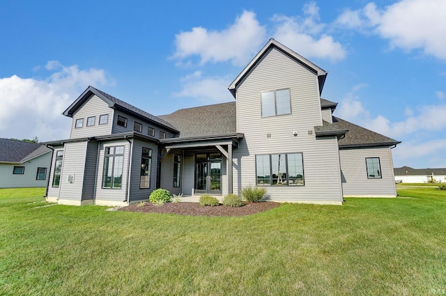 rear view of property with a shingled roof and a yard