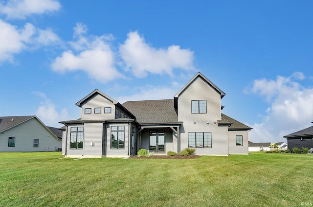 rear view of house featuring a lawn and a shingled roof