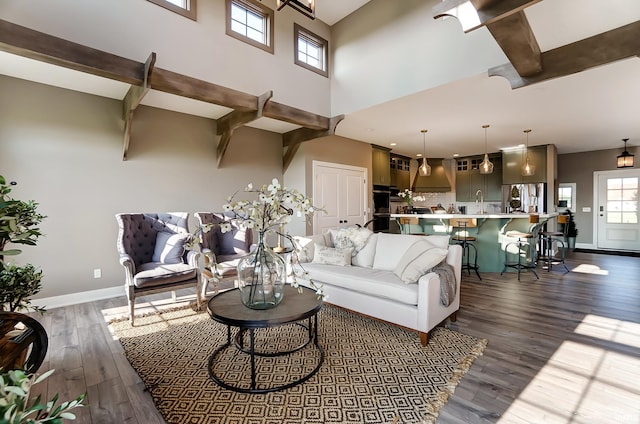 living area featuring a wealth of natural light, beamed ceiling, baseboards, and dark wood-style floors