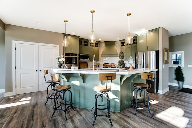 kitchen featuring appliances with stainless steel finishes, light countertops, green cabinets, and premium range hood