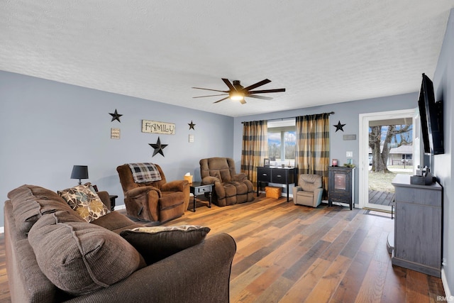 living room with a textured ceiling, dark wood-style floors, and a ceiling fan