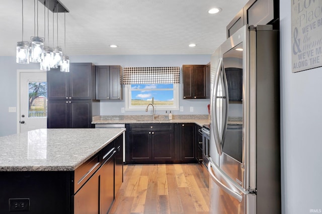 kitchen featuring light wood-style flooring, smart refrigerator, a sink, a center island, and light stone countertops