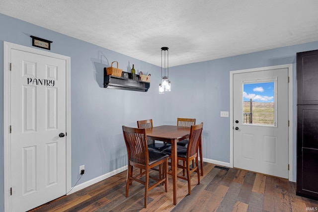 dining area featuring baseboards, dark wood-style flooring, and a textured ceiling