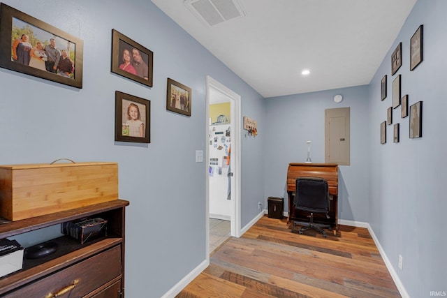 hallway featuring electric panel, visible vents, light wood-type flooring, and baseboards