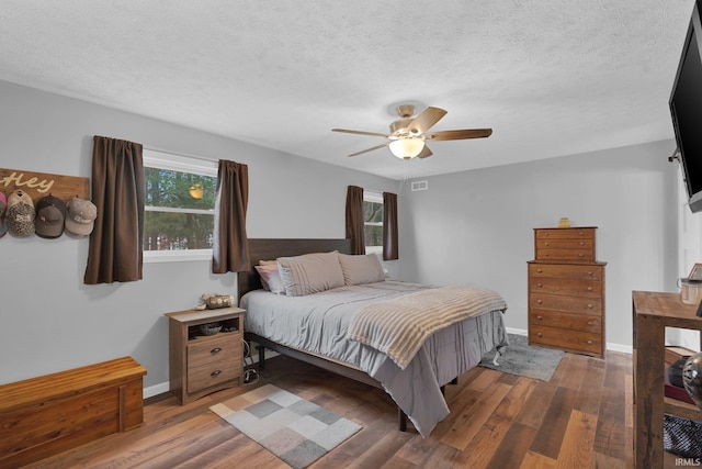 bedroom with a ceiling fan, wood finished floors, baseboards, and a textured ceiling