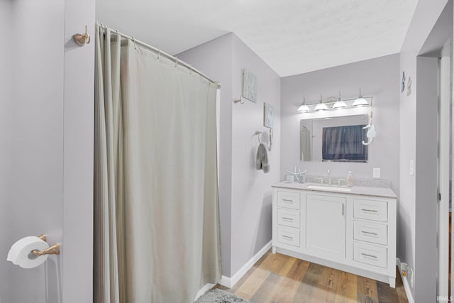 full bath with baseboards, wood finished floors, and vanity