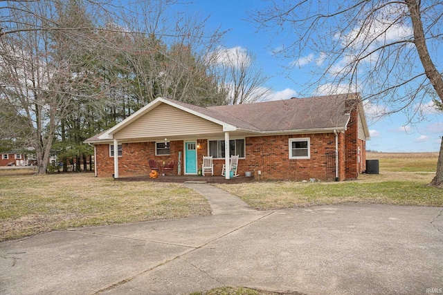 single story home with a front lawn, brick siding, covered porch, and roof with shingles