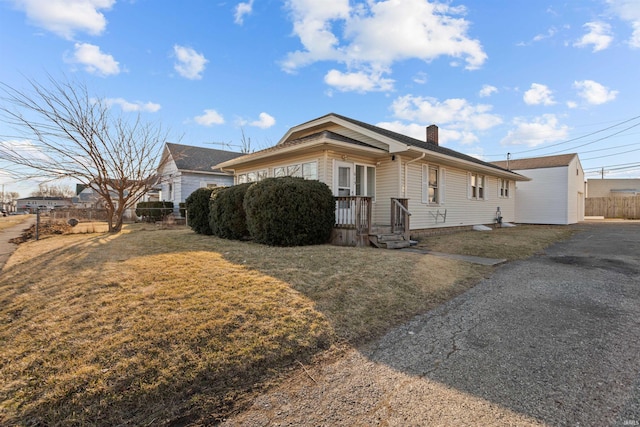 view of side of home with fence, a lawn, and a chimney