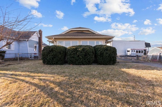 view of side of property featuring a lawn and fence