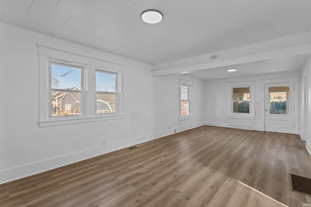 empty room featuring visible vents, baseboards, and wood finished floors