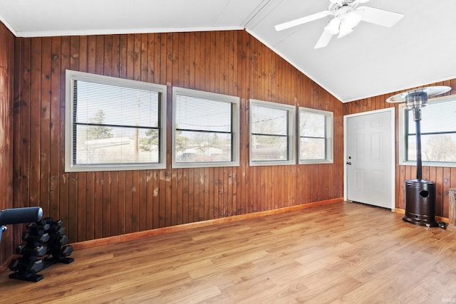 spare room featuring baseboards, lofted ceiling, wooden walls, and wood finished floors