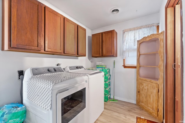 laundry room with light wood-type flooring, baseboards, visible vents, and washing machine and clothes dryer