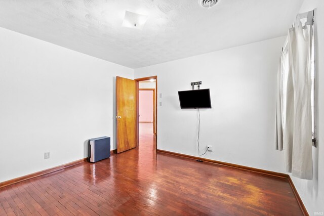 unfurnished room featuring hardwood / wood-style floors, visible vents, and baseboards