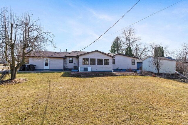 rear view of property with a sunroom, a lawn, an outdoor structure, and a patio area