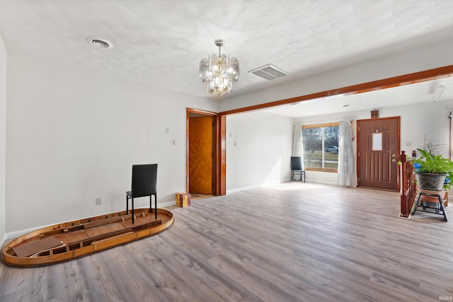 interior space featuring visible vents, baseboards, wood finished floors, and a chandelier