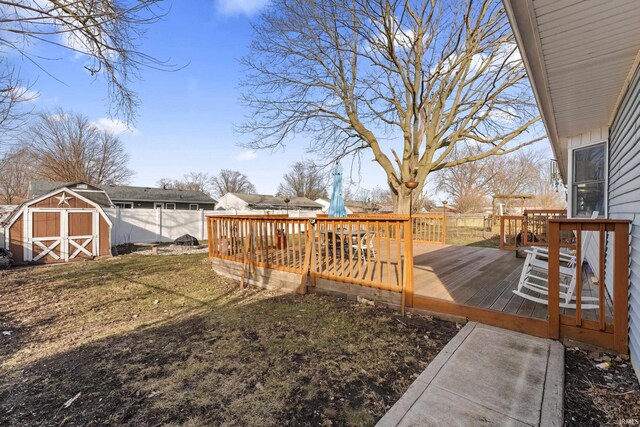 view of yard with an outbuilding, a storage unit, fence, and a wooden deck