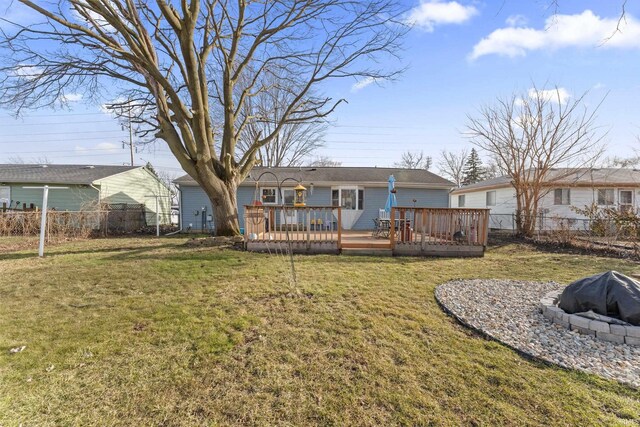 back of house featuring a yard, a fire pit, a wooden deck, and a fenced backyard