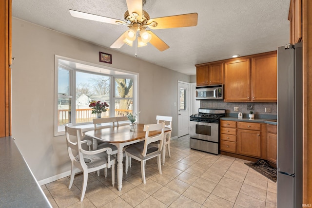 kitchen featuring a textured ceiling, tasteful backsplash, brown cabinets, and stainless steel appliances