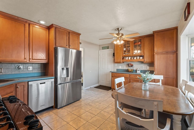 kitchen featuring tasteful backsplash, light tile patterned flooring, brown cabinets, and stainless steel appliances