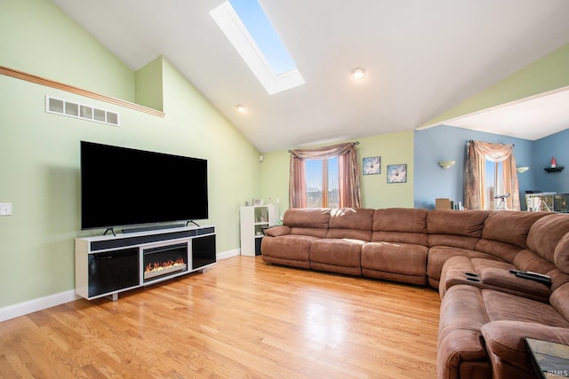 living room featuring baseboards, visible vents, a skylight, and light wood-style floors