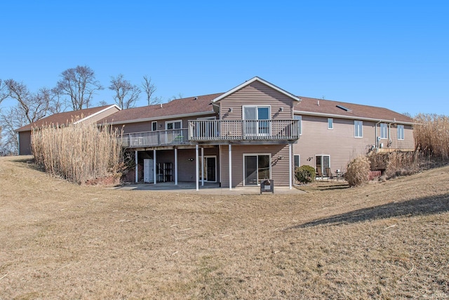 rear view of house with a wooden deck, a patio, and a lawn