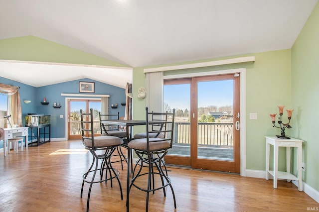 dining room with baseboards, wood finished floors, and vaulted ceiling