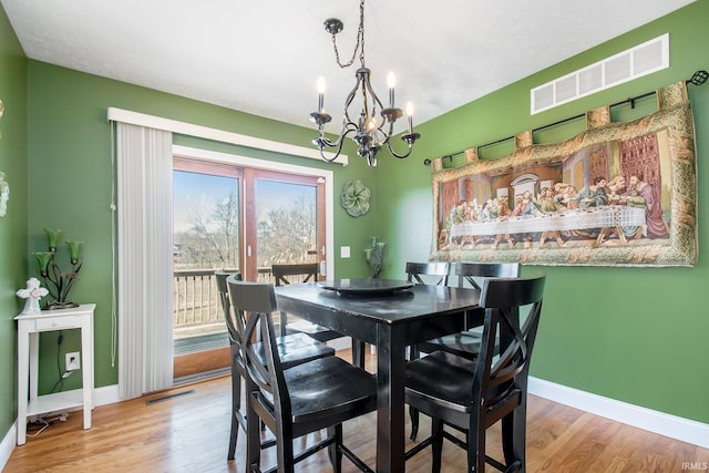 dining room featuring visible vents, an inviting chandelier, baseboards, and wood finished floors