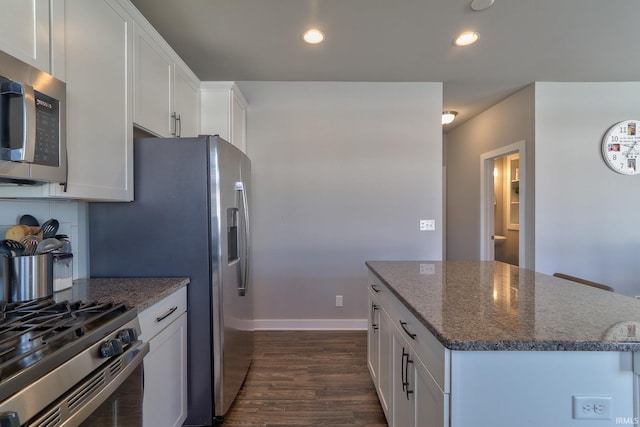 kitchen featuring dark stone countertops, dark wood-style floors, recessed lighting, stainless steel appliances, and white cabinetry