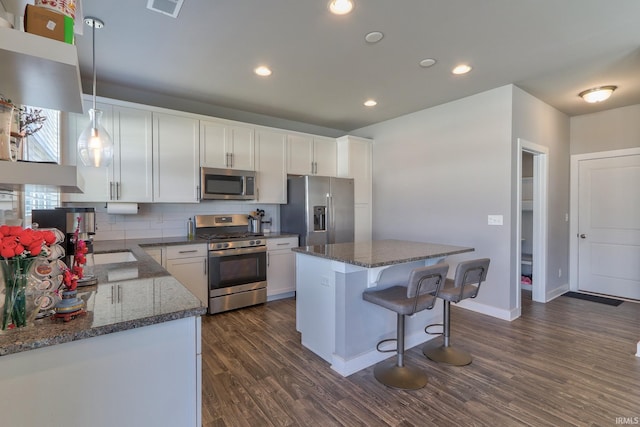 kitchen with white cabinetry, dark wood-type flooring, a kitchen island, and stainless steel appliances