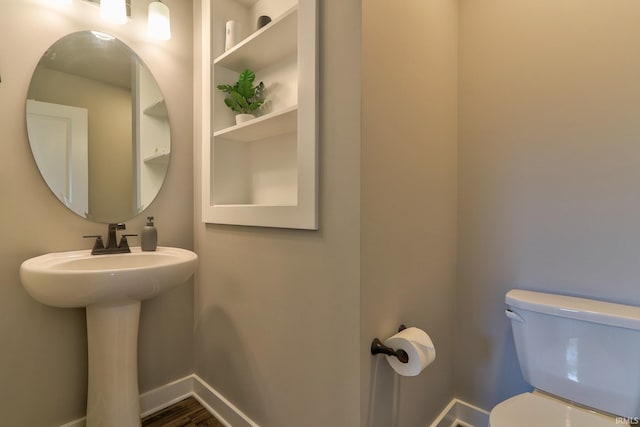 bathroom featuring toilet, baseboards, and a sink