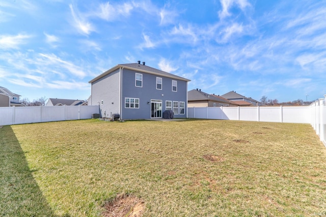 rear view of property featuring a lawn, central AC, and a fenced backyard