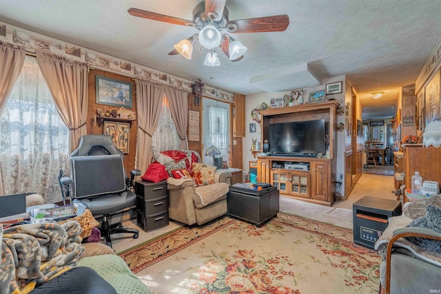 living area with carpet floors, a textured ceiling, and a ceiling fan