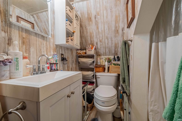 bathroom featuring vanity, toilet, and wood walls