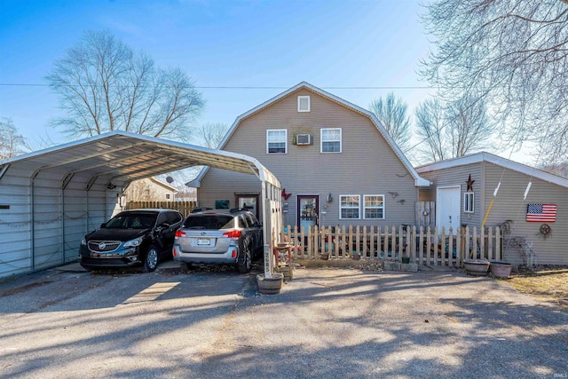 colonial inspired home with a detached carport, fence, a gambrel roof, and driveway