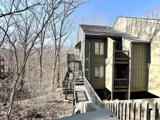 view of side of home with stairs and roof with shingles