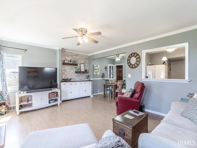 living room featuring light wood-type flooring, baseboards, ceiling fan, and crown molding