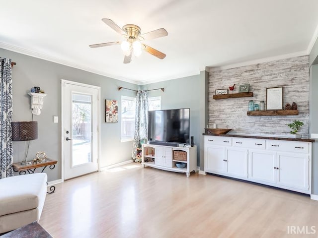 unfurnished living room with light wood-style flooring, baseboards, a ceiling fan, and ornamental molding