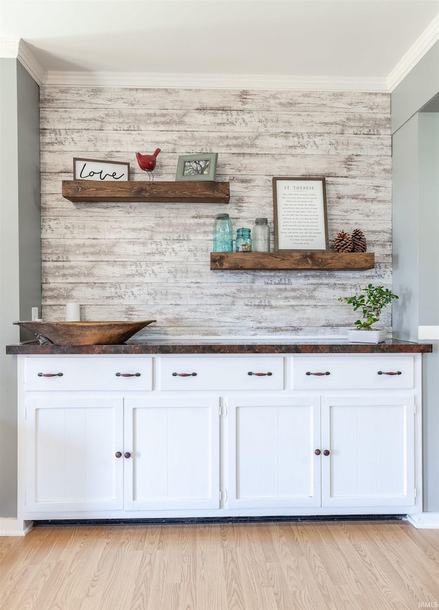 bar featuring light wood finished floors and crown molding