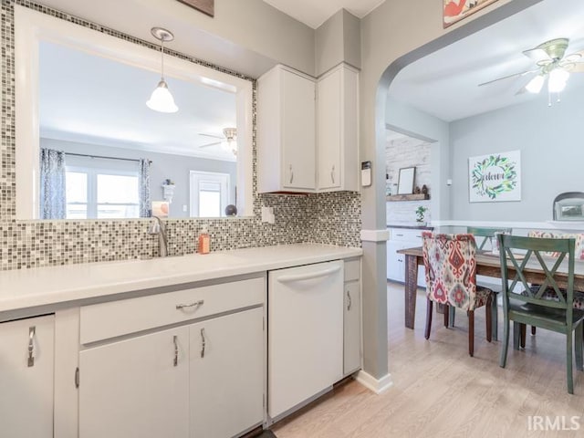 kitchen with white dishwasher, ceiling fan, a sink, light countertops, and tasteful backsplash