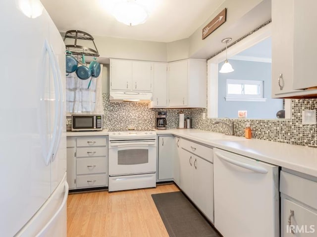 kitchen featuring under cabinet range hood, white appliances, backsplash, and light countertops