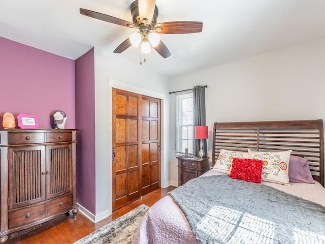 bedroom featuring a closet, baseboards, wood finished floors, and a ceiling fan