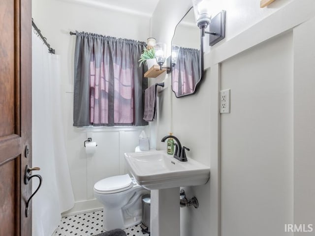 full bath featuring toilet, a shower with shower curtain, and a sink