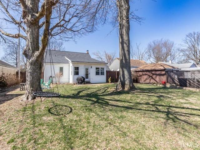 rear view of house with a lawn and fence