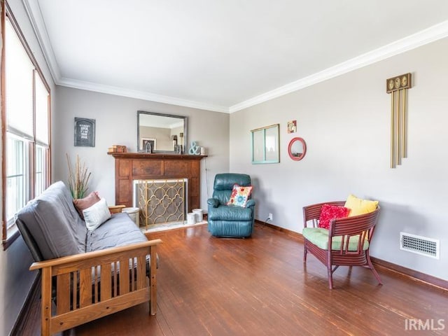 living room featuring visible vents, crown molding, baseboards, a fireplace, and wood finished floors