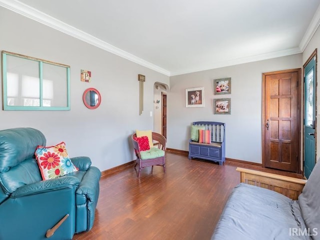 sitting room featuring arched walkways, wood finished floors, baseboards, and ornamental molding