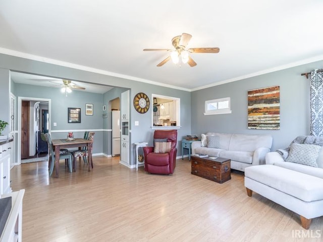 living room featuring light wood finished floors, baseboards, ceiling fan, and ornamental molding